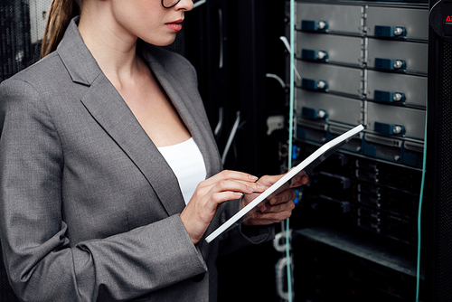cropped view of businesswoman using digital tablet near server rack