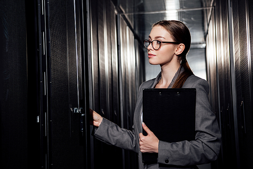 beautiful businesswoman in glasses holding clipboard in data center