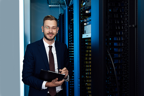 happy businessman in glasses holding clipboard in data center