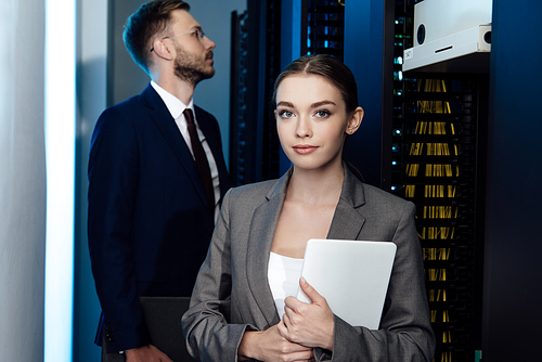 selective focus of attractive businesswoman holding digital tablet near businessman in data center