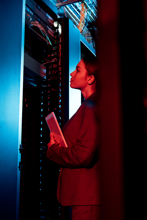 selective focus of attractive businesswoman looking at server rack and holding digital tablet