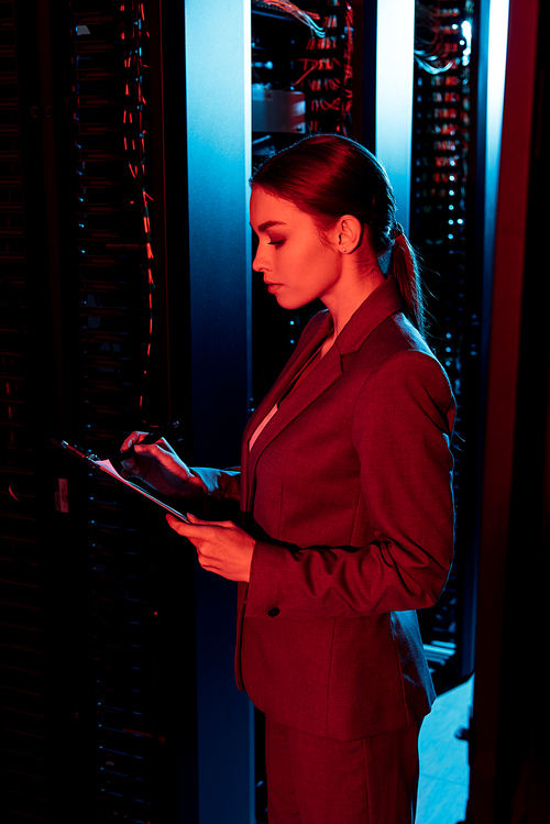 side view of businesswoman holding clipboard in server room