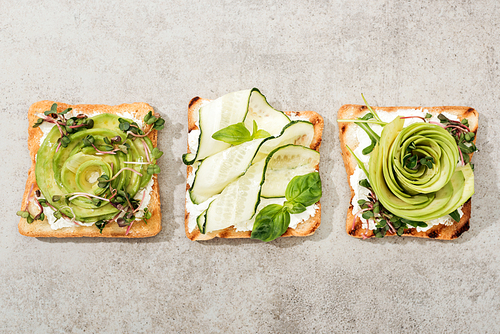 Top view of toasts with cut vegetables on texture surface