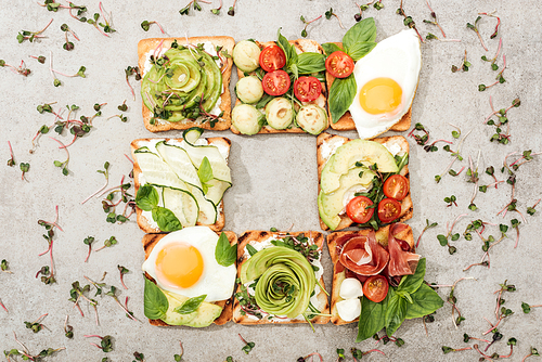 top view of toasts with s, fried eggs and prosciutto on textured surface