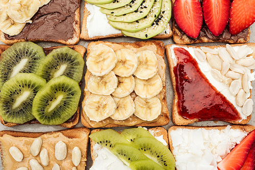 Top view of toasts with cut fruits, berries and peanuts