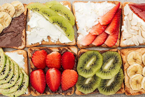 Top view of toasts with cut fruits, strawberry and peanuts