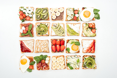 Top view of toasts with cut fruits, vegetables and peanuts on white