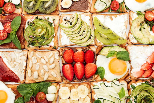 Top view of toasts with cut fruits, vegetables and peanuts