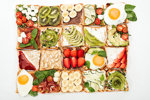top view of toasts with cut fruits, s and peanuts on white