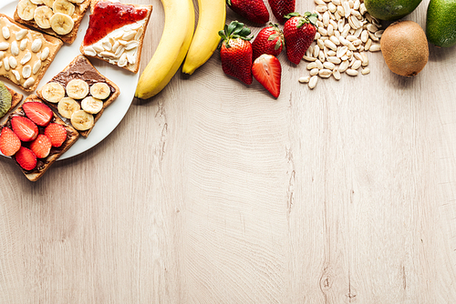 top view of bananas, strawberries, peanuts and toasts on wooden table with copy space