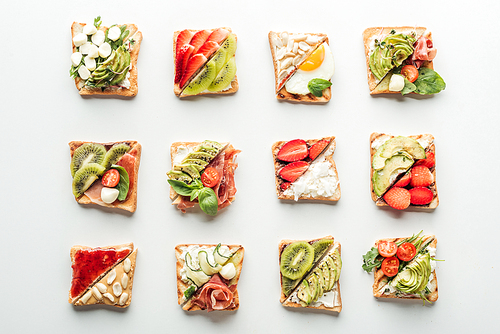 top view of tasty toasts with fruits, s and basil isolated on white