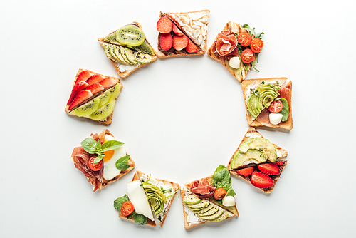 top view of toasts with fruits and s arranged in frame isolated on white with copy space