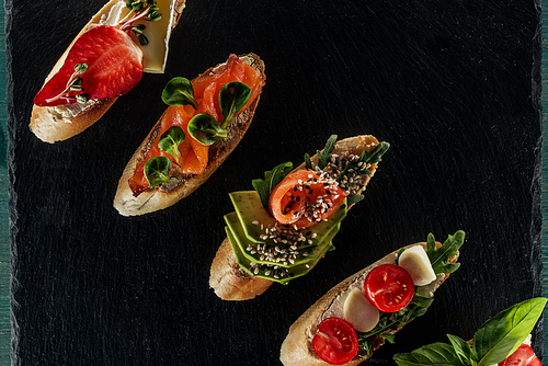 top view of italian bruschetta with salmon, tomatoes and avocado on wooden table