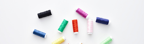 panoramic shot of bright and colorful threads on white background