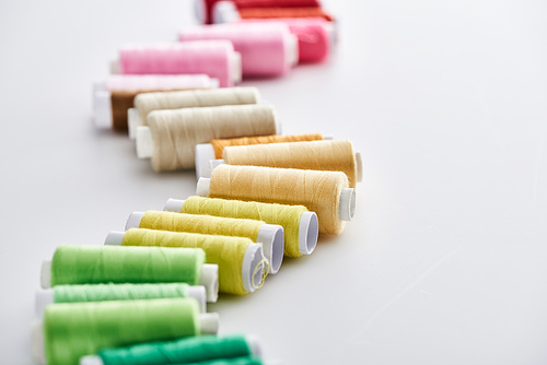 selective focus of bright and colorful threads on white background
