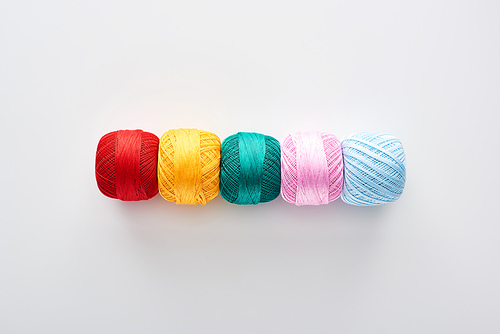 top view of bright and colorful knitting yarn balls on white background