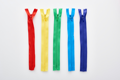top view of bright and colorful zippers on white background