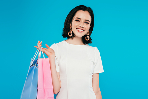 smiling elegant woman in dress with shopping bags isolated on blue