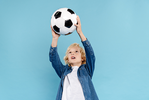 cute kid playing with football isolated on blue with copy space