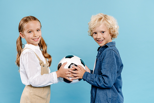 smiling and cute kids holding football isolated on blue