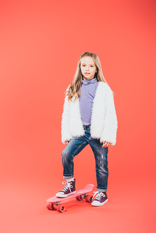 full length view of kid standing on skateboard on red