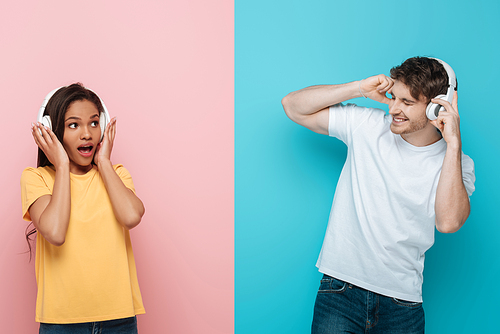 collage of shocked african american girl and excited young man listening music in wireless headphones on blue and pink background