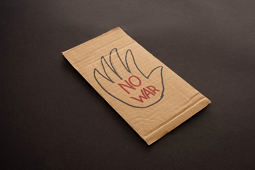 cardboard placard with no war lettering and hand on black background