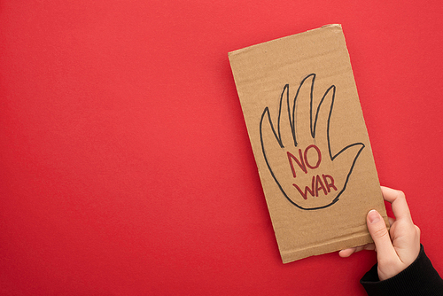 top view of woman holding cardboard placard with no war lettering on red background