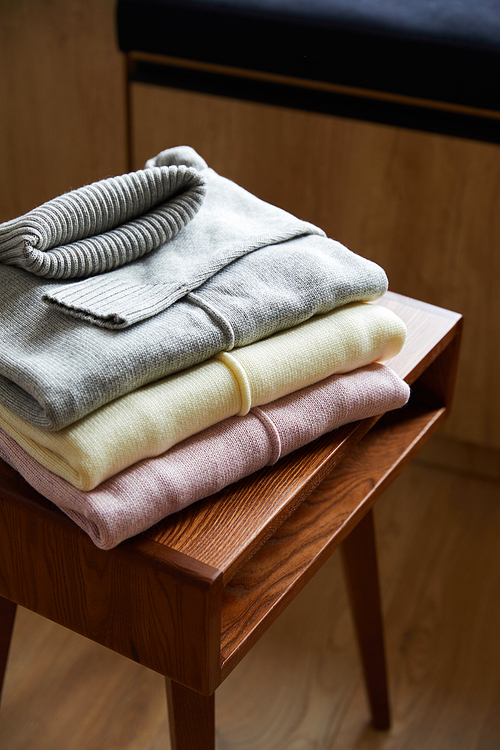 pink, beige and grey knitted soft sweaters on wooden table in room