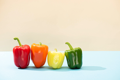 fresh colorful bell peppers on blue surface isolated on beige