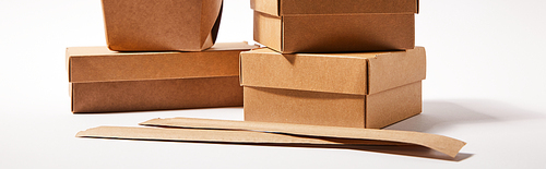 horizontal image of chopsticks in paper packaging near takeaway boxes with chinese food on white