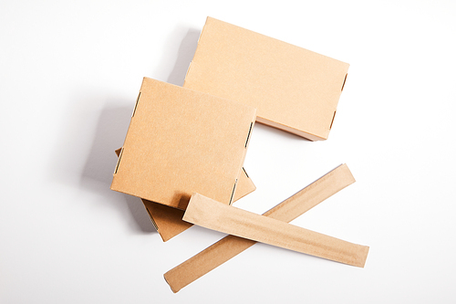 top view chopsticks in paper packaging near takeaway boxes with chinese food on white
