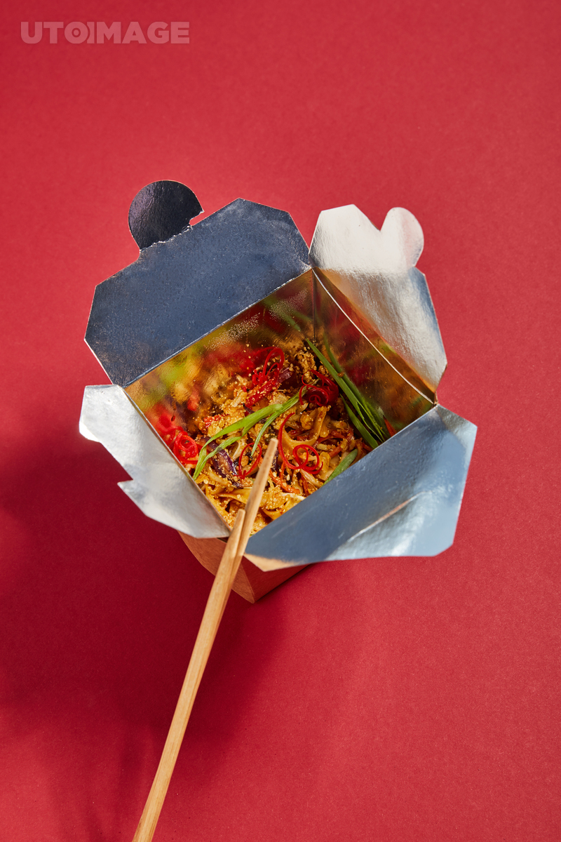 유토이미지 | top view of wooden chopsticks near tasty noodles with vegetables in takeaway box on red
