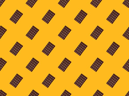 top view of sweet dark chocolate bars on orange colorful background, seamless pattern