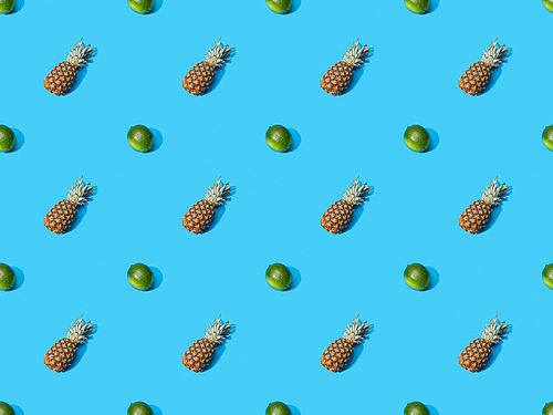 top view of whole ripe pineapples and limes on blue colorful background, seamless pattern