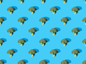top view of fresh green broccoli on blue background, seamless pattern