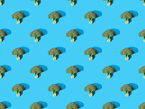 top view of fresh green broccoli on blue background, seamless pattern