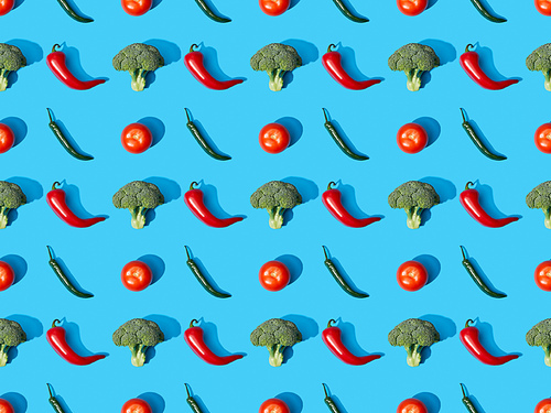 top view of fresh green broccoli, chili peppers and tomatoes on blue background, seamless pattern