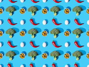top view of fresh green broccoli, eggs, chili peppers and olives on blue background, seamless pattern