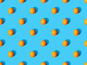 top view of ripe oranges on blue colorful background, seamless pattern