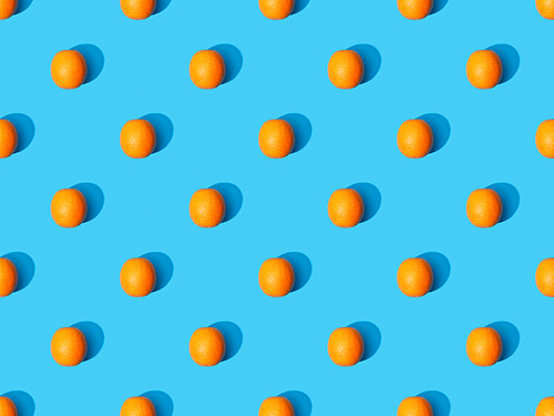 top view of ripe oranges on blue colorful background, seamless pattern