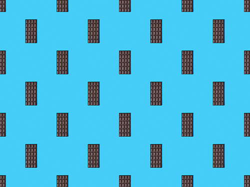 top view of sweet dark chocolate bars on blue colorful background, seamless pattern