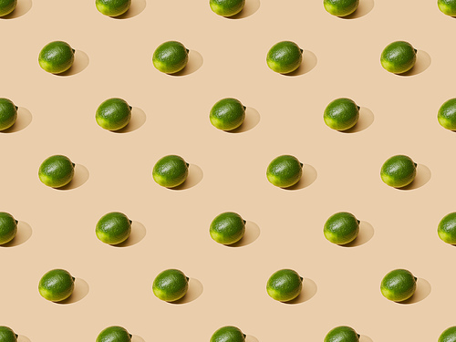 fresh whole limes on beige background, seamless pattern