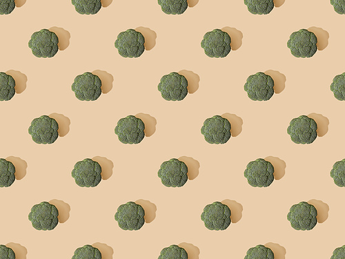 top view of fresh green broccoli on beige background, seamless pattern