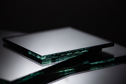 close up view of square mirror pieces in stack on black