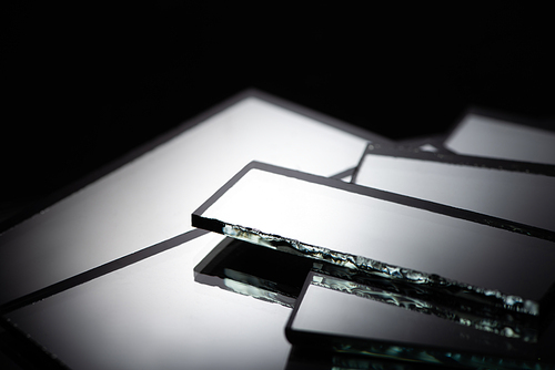 close up view of mirror pieces in stack on black background