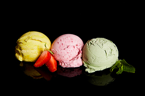 delicious lemon, strawberry and mint ice cream balls isolated on black