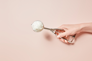 cropped view of woman holding fresh tasty ice cream ball in scoop on pink background