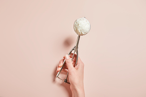 cropped view of woman holding fresh tasty ice cream ball in scoop on pink background
