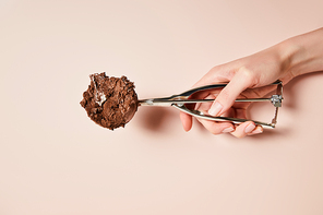 cropped view of woman holding scoop with chocolate ice cream ball on pink background